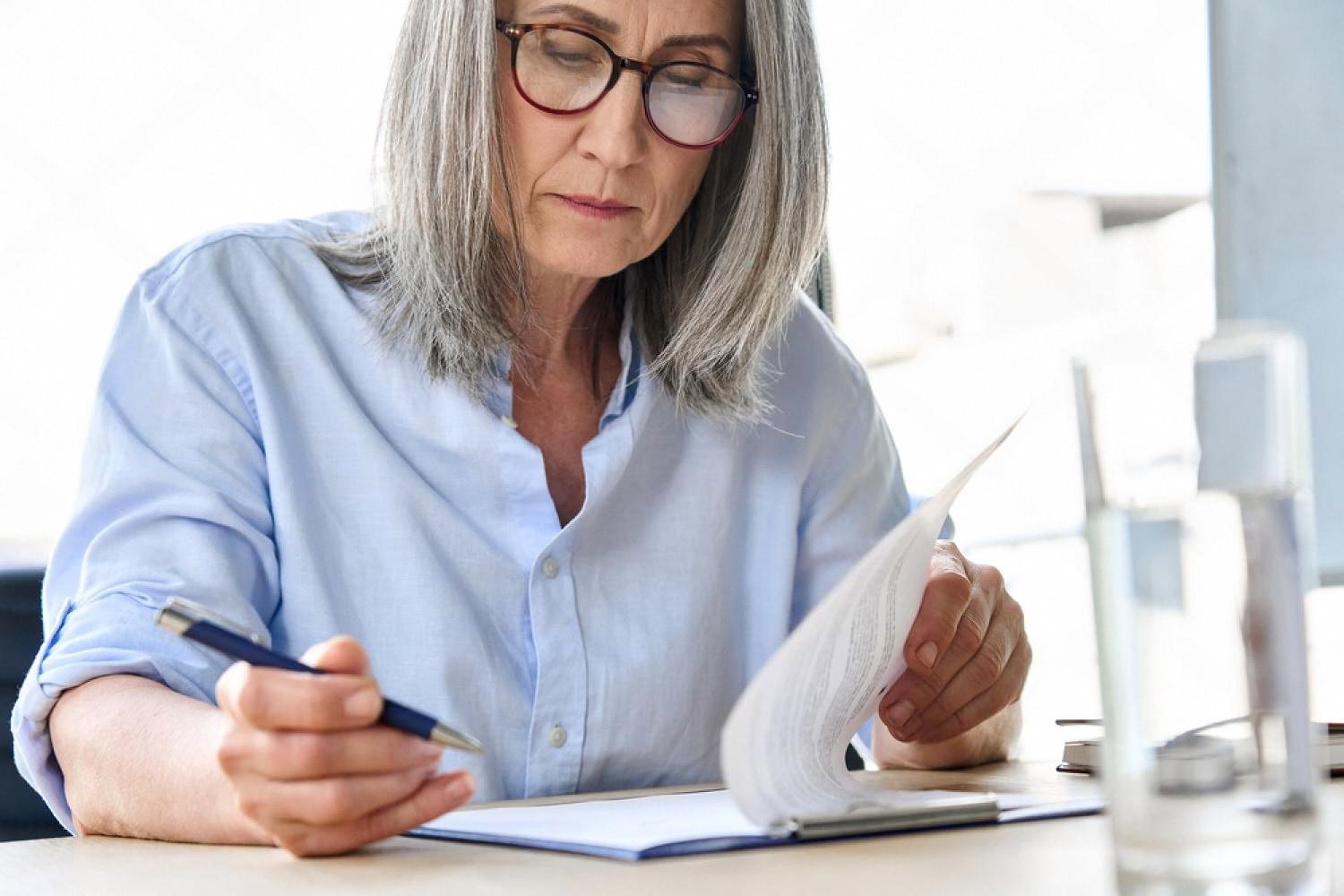 Senior HR consultant reviewing company policy documents at her desk